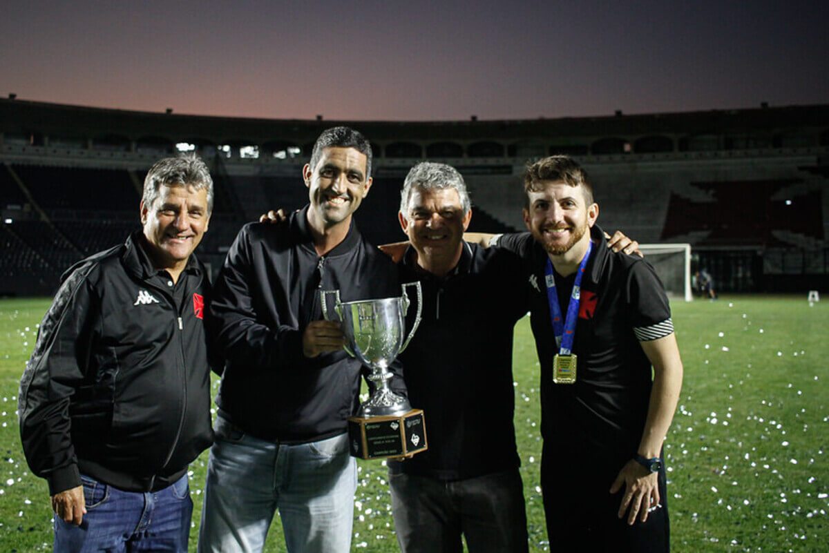 Carlos Brazil comemora o título Carioca ao lado do CEO Luiz Mello (segurando o troféu), o técnico William Batista (à direita) e Eduardo Húngaro (à esquerda)