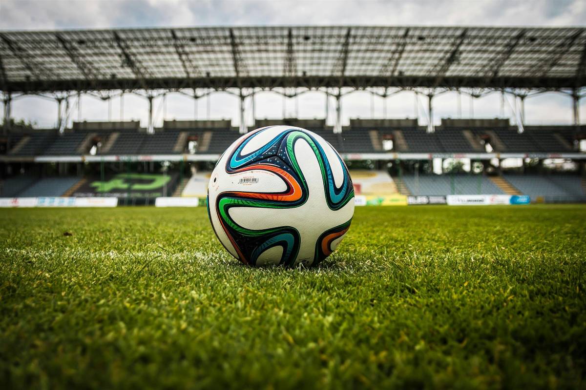 Bola de futebol em campo oficial com a grama verde